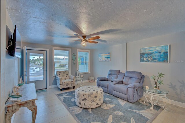 living room with ceiling fan, light tile patterned floors, and a textured ceiling