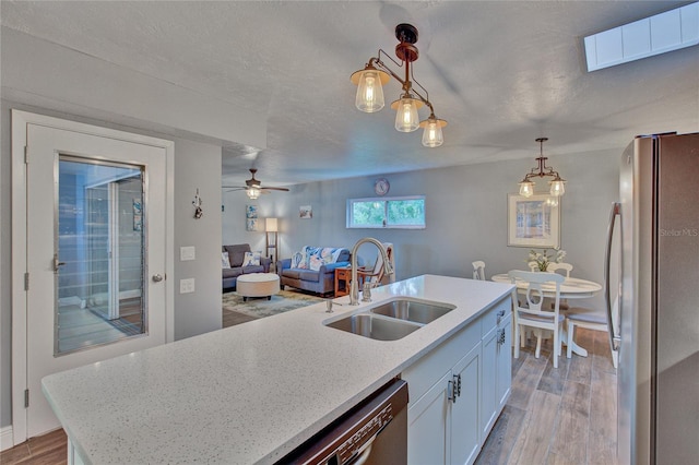 kitchen featuring white cabinetry, light hardwood / wood-style flooring, stainless steel appliances, sink, and hanging light fixtures