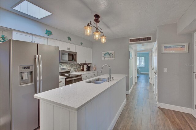 kitchen featuring light hardwood / wood-style flooring, stainless steel appliances, white cabinetry, sink, and pendant lighting