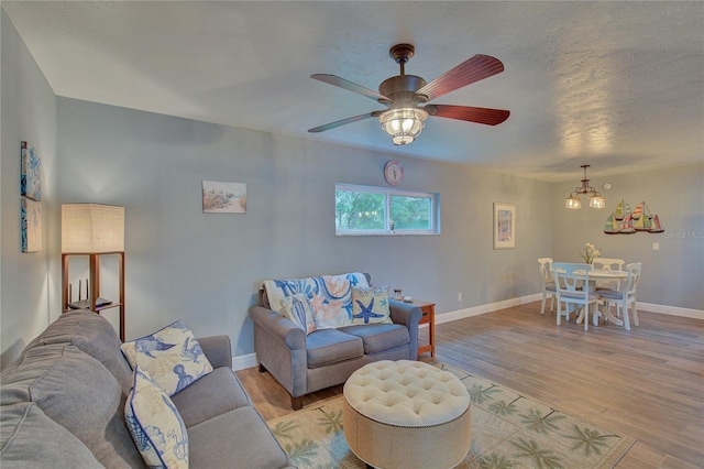 living room featuring light hardwood / wood-style flooring and ceiling fan with notable chandelier