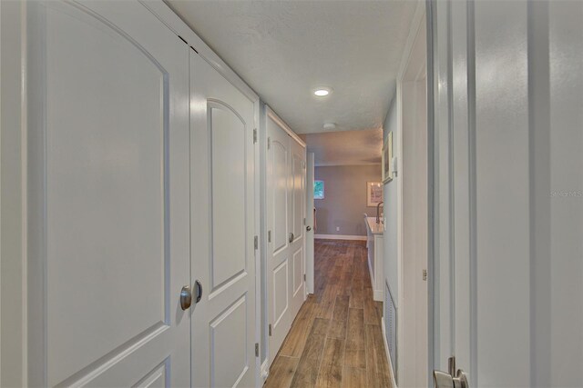 hall with light wood-type flooring and a textured ceiling