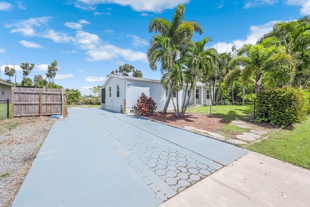 view of front of house with concrete driveway, a front yard, and fence