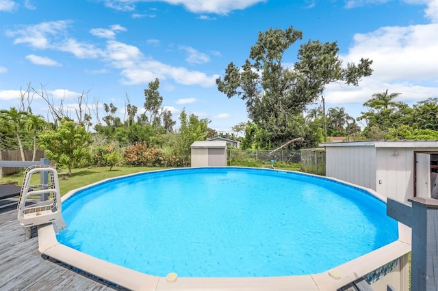 view of pool featuring a storage shed, a lawn, and a wooden deck