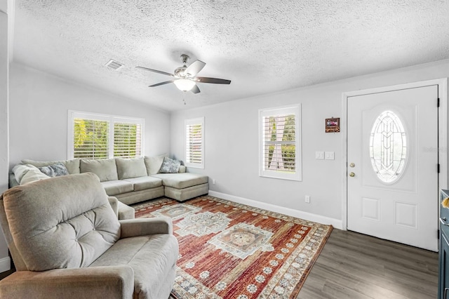 living room with ceiling fan, a wealth of natural light, dark hardwood / wood-style flooring, and a textured ceiling