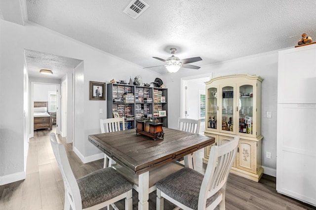 dining area with vaulted ceiling, a textured ceiling, hardwood / wood-style flooring, and ceiling fan