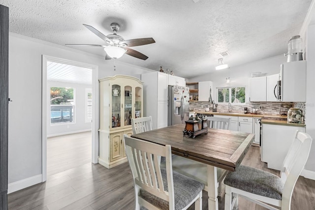 dining room with hardwood / wood-style flooring, a textured ceiling, sink, ceiling fan, and ornamental molding