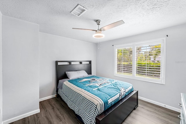 bedroom featuring hardwood / wood-style floors, ceiling fan, and a textured ceiling