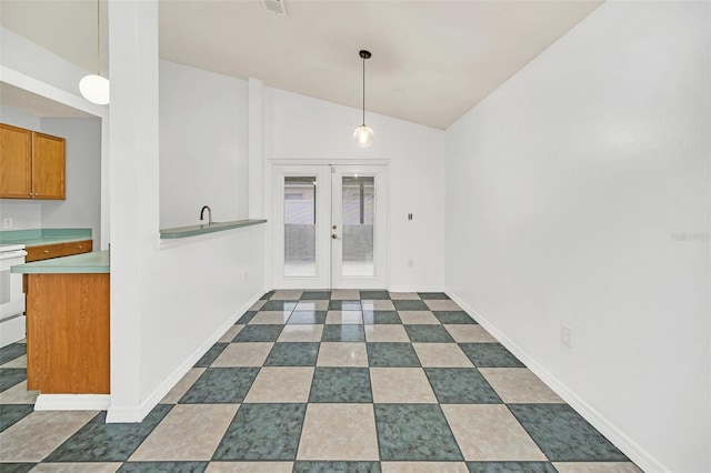 unfurnished dining area with vaulted ceiling, dark tile patterned floors, and french doors