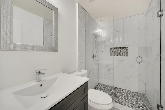 bathroom with toilet, vanity, a textured ceiling, and walk in shower