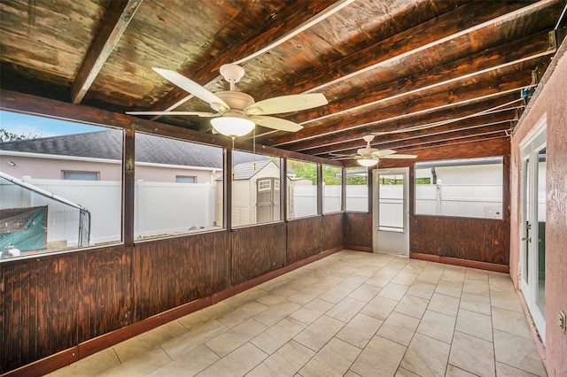 unfurnished sunroom featuring beam ceiling, ceiling fan, and wood ceiling