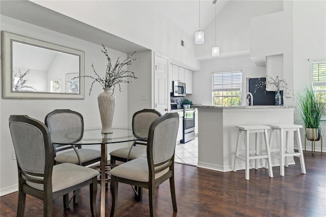 dining room with dark wood-type flooring and high vaulted ceiling