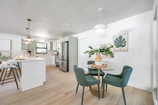 dining space featuring light wood-type flooring and sink