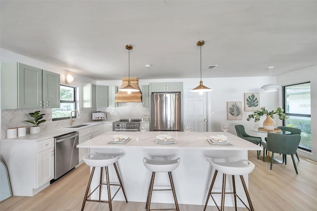 kitchen with a kitchen island, custom exhaust hood, sink, and appliances with stainless steel finishes