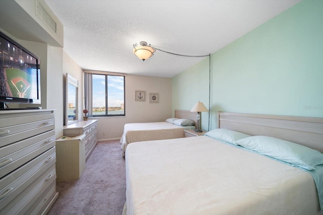 bedroom with light colored carpet and a textured ceiling