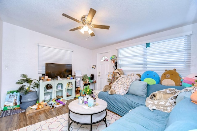 living room with ceiling fan, light hardwood / wood-style floors, a textured ceiling, and vaulted ceiling