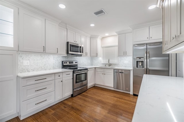 kitchen with dark hardwood / wood-style floors, appliances with stainless steel finishes, sink, light stone counters, and white cabinets