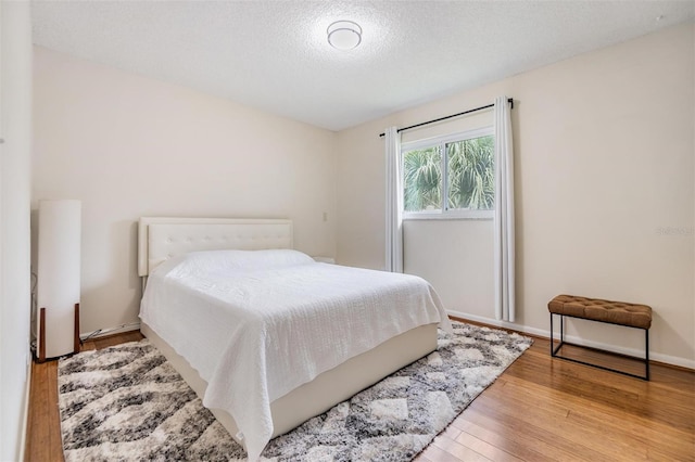 bedroom with a textured ceiling and light wood-type flooring