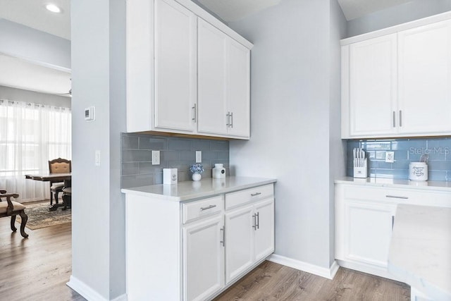 bar with backsplash, white cabinetry, and light hardwood / wood-style flooring