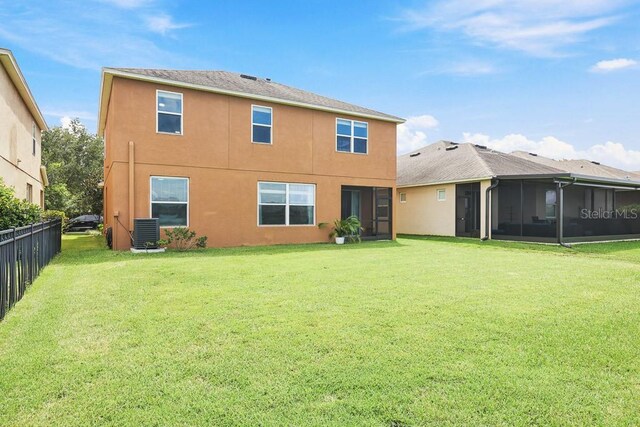 back of house with a sunroom, a lawn, and central AC