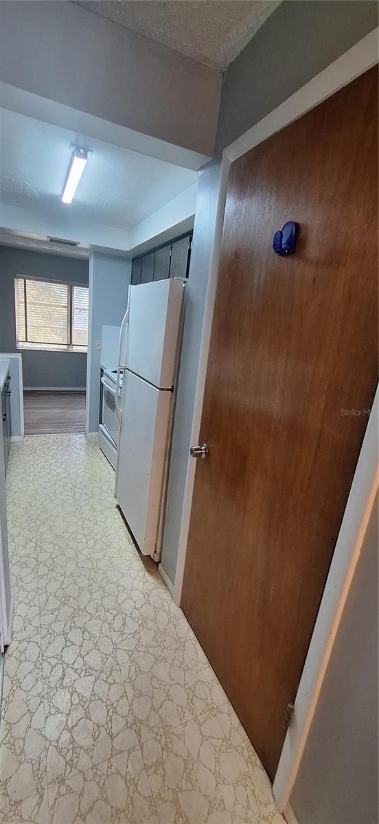 kitchen featuring a textured ceiling, white fridge, and stainless steel stove