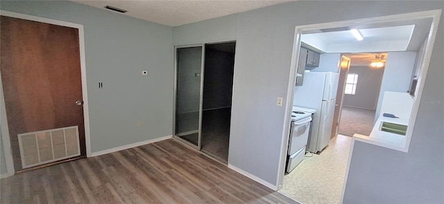 unfurnished bedroom with hardwood / wood-style floors, white fridge, sink, and a textured ceiling