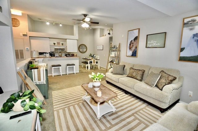 carpeted living room with rail lighting, ceiling fan, and sink