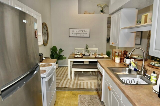 kitchen featuring white electric range, stainless steel fridge, white cabinetry, and sink