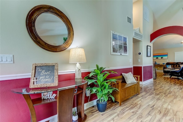 interior space with wood finished floors, visible vents, and a towering ceiling