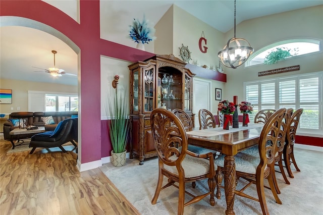 dining room featuring plenty of natural light, arched walkways, light wood finished floors, and high vaulted ceiling
