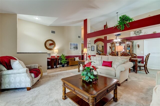 living area featuring light carpet, visible vents, and high vaulted ceiling