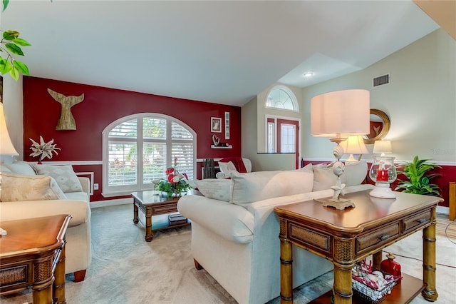 living room featuring visible vents, light colored carpet, and vaulted ceiling