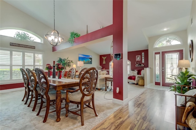 carpeted dining room with plenty of natural light, high vaulted ceiling, and a chandelier