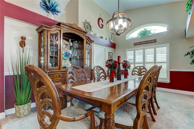 dining area featuring a notable chandelier, plenty of natural light, light carpet, and a towering ceiling