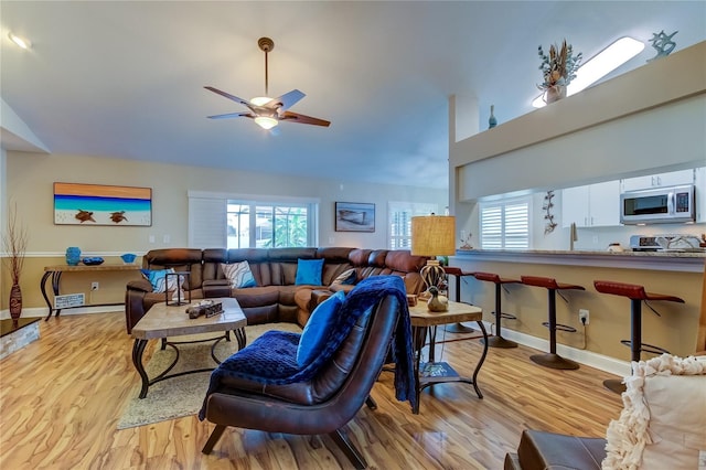 living room with light wood-style flooring, baseboards, high vaulted ceiling, and ceiling fan