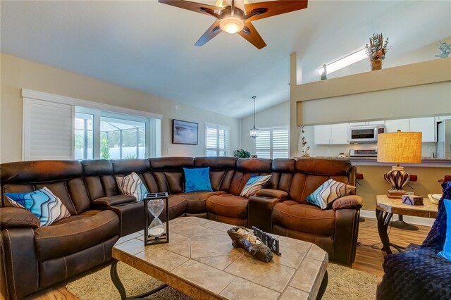 living area featuring vaulted ceiling, light wood-style flooring, a wealth of natural light, and ceiling fan