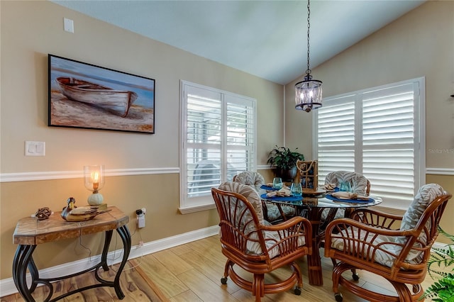 dining space featuring baseboards, lofted ceiling, an inviting chandelier, and wood finished floors