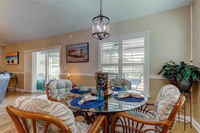 dining space with light wood-style flooring, a notable chandelier, and baseboards