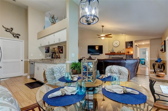 dining area with lofted ceiling, ceiling fan with notable chandelier, light hardwood / wood-style floors, and sink