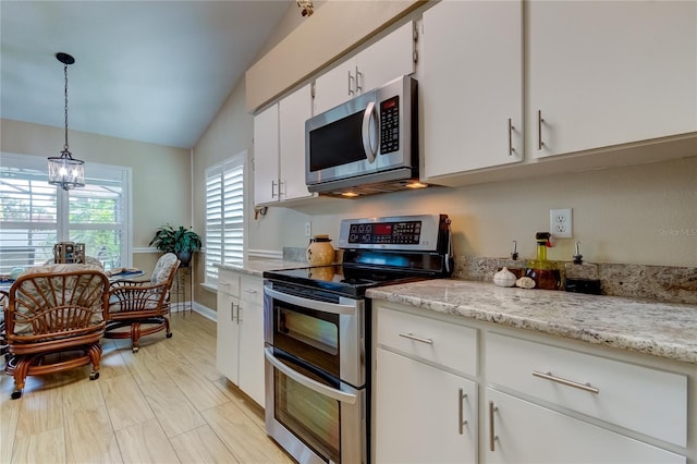 kitchen with light stone countertops, lofted ceiling, white cabinets, appliances with stainless steel finishes, and pendant lighting