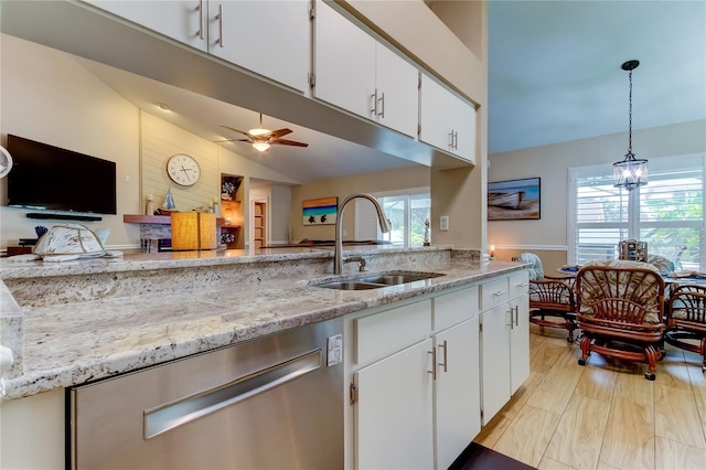 kitchen featuring light stone countertops, dishwasher, vaulted ceiling, white cabinetry, and a sink