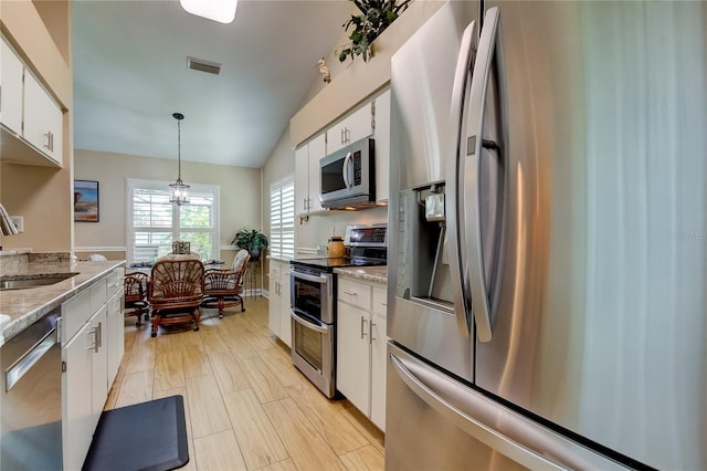 kitchen with white cabinetry, light stone counters, stainless steel appliances, and decorative light fixtures