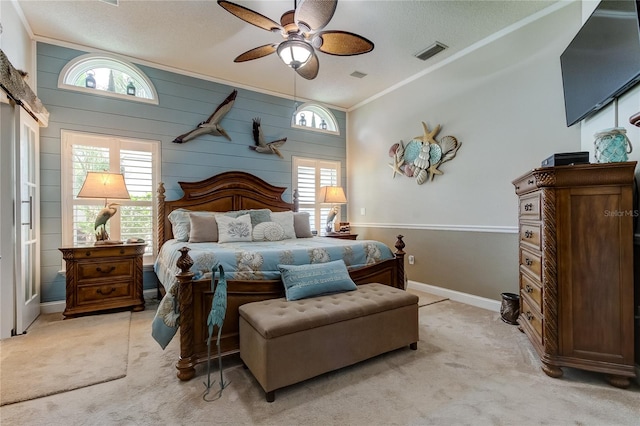 bedroom with light carpet, ornamental molding, a textured ceiling, wood walls, and ceiling fan