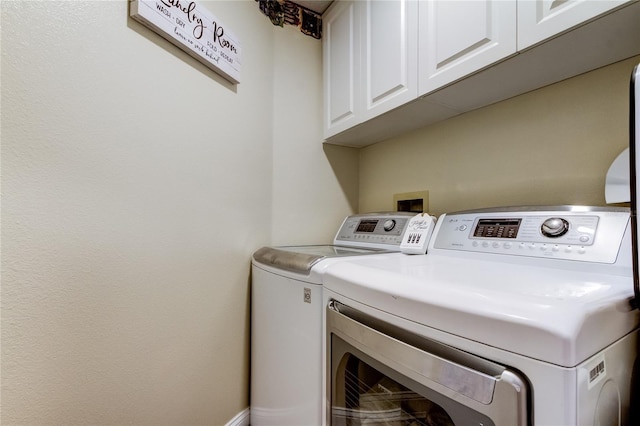 clothes washing area featuring cabinet space and washer and clothes dryer