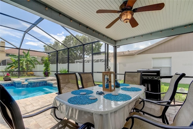 view of patio / terrace with a lanai, fence, a pool with connected hot tub, and ceiling fan