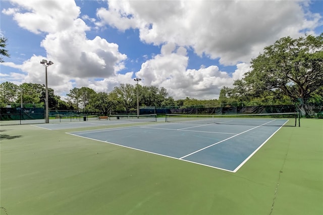 view of tennis court with community basketball court and fence