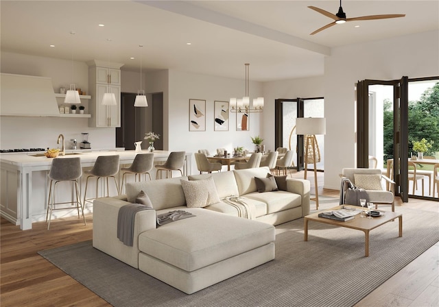 living room with ceiling fan with notable chandelier and light hardwood / wood-style flooring