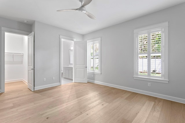 unfurnished bedroom with light hardwood / wood-style floors, a spacious closet, multiple windows, and ensuite bathroom