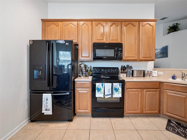 kitchen featuring black appliances, light tile patterned floors, and sink