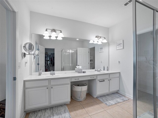 bathroom featuring tile patterned flooring, a shower with door, and vanity