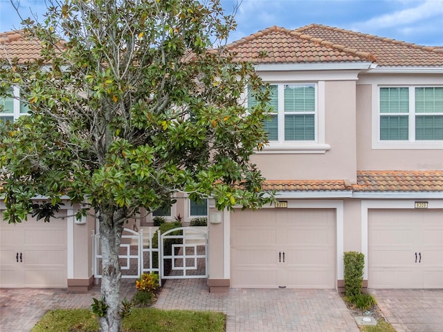 townhome / multi-family property featuring stucco siding, a tile roof, and decorative driveway